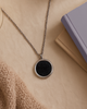 Necklace with a black pendant on a beige surface